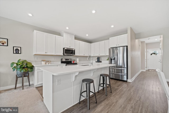 346 Goodwick Dr, Middletown, DE 19709 - kitchen with appliances with stainless steel finishes, light countertops, a center island with sink, white cabinets, and a breakfast bar area
