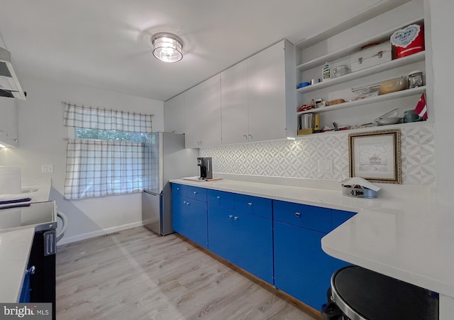 12987 Holly Way, Lusby, MD 20657 - kitchen with blue cabinetry, open shelves, light wood finished floors, backsplash, and light countertops