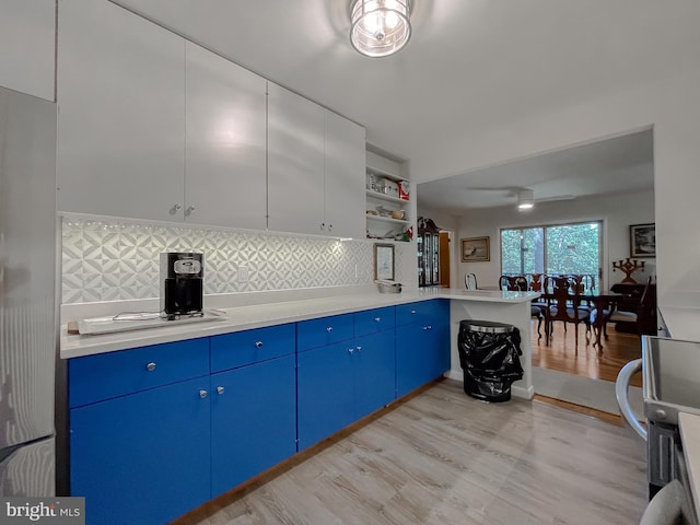 12987 Holly Way, Lusby, MD 20657 - kitchen with blue cabinetry, light wood finished floors, light countertops, and backsplash