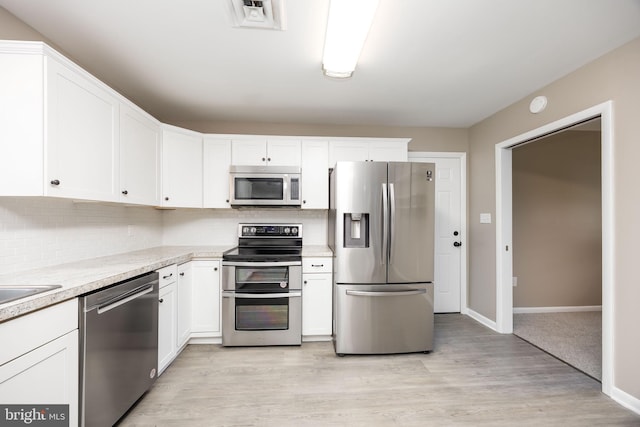 7043 Cromwell Ave, Salisbury, MD 21804 - kitchen featuring appliances with stainless steel finishes, light countertops, white cabinetry, decorative backsplash, and light wood-type flooring