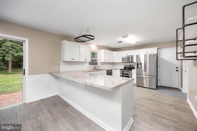 7043 Cromwell Ave, Salisbury, MD 21804 - kitchen featuring appliances with stainless steel finishes, light countertops, a peninsula, white cabinetry, and light wood-style flooring
