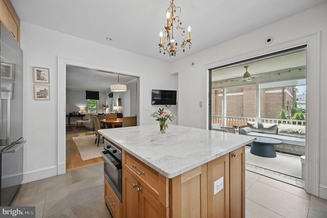 1646 Foxhall Rd NW, Washington, DC 20007 - kitchen with appliances with stainless steel finishes, a kitchen island, light stone counters, light tile patterned floors, and decorative light fixtures