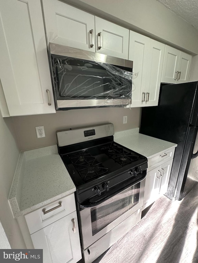 1730 Fountain Rock Way Unit 1730-C, Edgewood, MD 21040 - kitchen with stainless steel appliances, white cabinets, light stone countertops, wood finished floors, and a textured ceiling