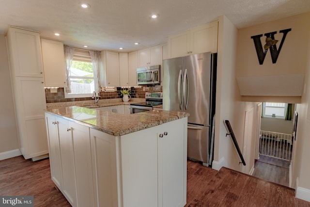 4328 Rolling Stone Way, Alexandria, VA 22306 - kitchen featuring appliances with stainless steel finishes, wood finished floors, light stone countertops, a center island, and tasteful backsplash