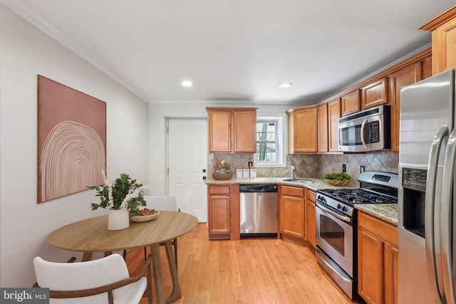 434 N Budd St, Philadelphia, PA 19104 - kitchen with appliances with stainless steel finishes, crown molding, light wood-type flooring, decorative backsplash, and light stone counters
