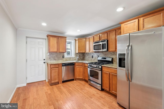 434 N Budd St, Philadelphia, PA 19104 - kitchen with appliances with stainless steel finishes, crown molding, backsplash, light stone counters, and light wood-style flooring