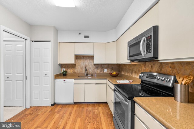 5501 Seminary Rd Unit 407S, Falls Church, VA 22041 - kitchen featuring appliances with stainless steel finishes, white cabinetry, light wood-style floors, tasteful backsplash, and a textured ceiling