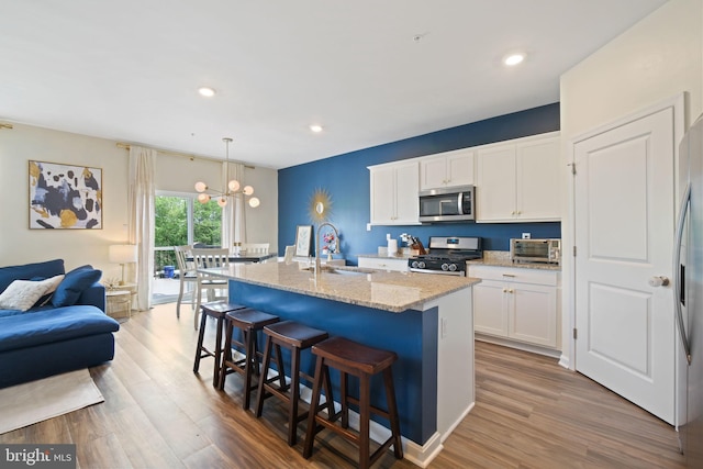 2014 Fauna Dr, Frederick, MD 21702 - kitchen featuring appliances with stainless steel finishes, wood finished floors, light stone countertops, a kitchen island with sink, and recessed lighting