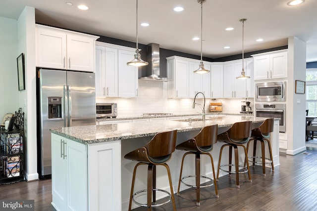 6006 Charles Xing, Ellicott City, MD 21043 - kitchen featuring appliances with stainless steel finishes, wall chimney exhaust hood, tasteful backsplash, recessed lighting, and a center island with sink