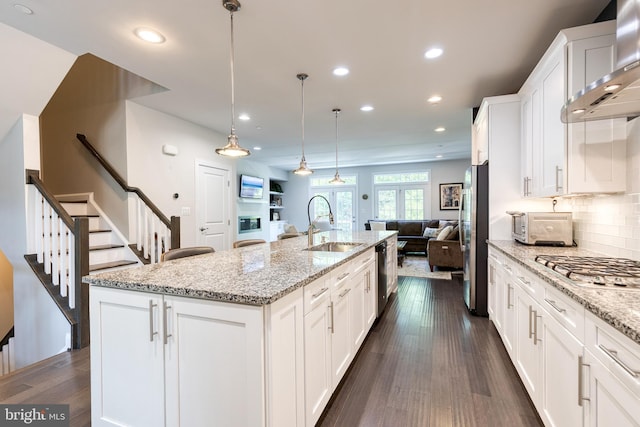 6006 Charles Xing, Ellicott City, MD 21043 - kitchen with wall chimney exhaust hood, open floor plan, stainless steel appliances, white cabinetry, and an island with sink