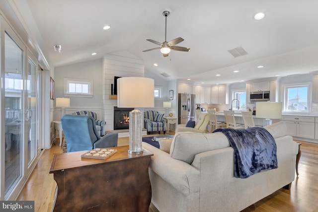 1510 N Bay Shore Dr, Milton, DE 19968 - living area with a large fireplace, ceiling fan, vaulted ceiling, healthy amount of natural light, and light wood-style flooring