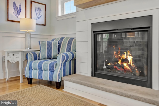1510 N Bay Shore Dr, Milton, DE 19968 - living area featuring wood finished floors, a warm lit fireplace, a wainscoted wall, and a decorative wall