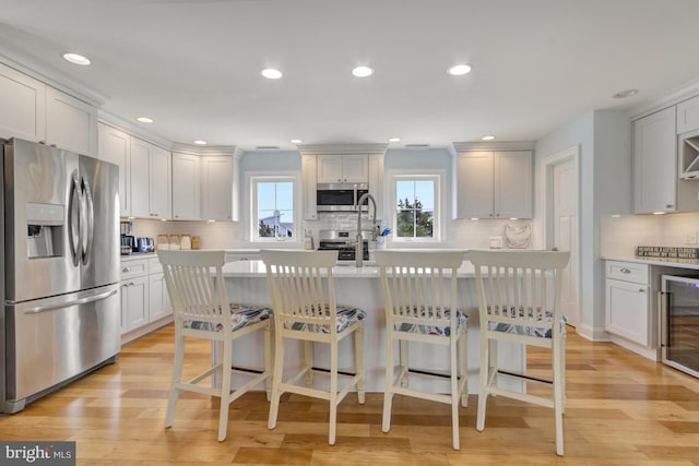 1510 N Bay Shore Dr, Milton, DE 19968 - kitchen featuring stainless steel appliances, wine cooler, decorative backsplash, light countertops, and a kitchen island with sink