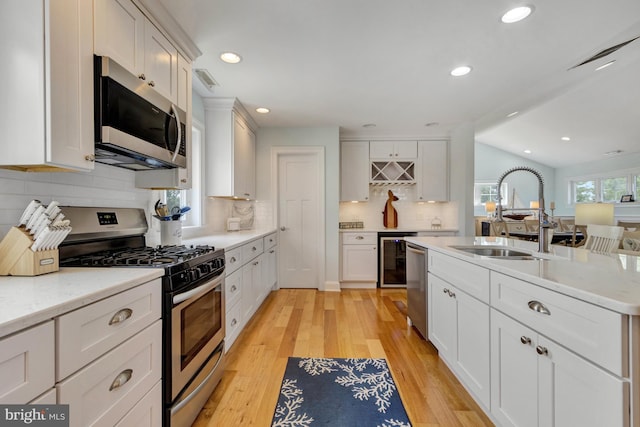 1510 N Bay Shore Dr, Milton, DE 19968 - kitchen with stainless steel appliances, decorative backsplash, light wood-style floors, white cabinetry, and recessed lighting