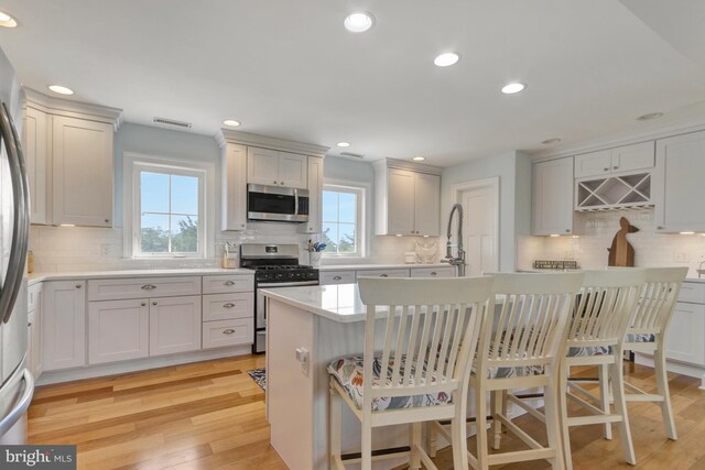 1510 N Bay Shore Dr, Milton, DE 19968 - kitchen with appliances with stainless steel finishes, tasteful backsplash, light wood-style flooring, light countertops, and a breakfast bar area