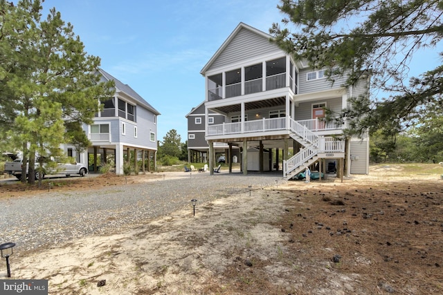 1510 N Bay Shore Dr, Milton, DE 19968 - raised beach house featuring a carport, stairway, dirt driveway, and a sunroom