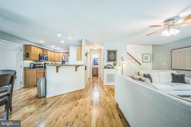 16206 Tiffany Ln, Haymarket, VA 20169 - kitchen featuring stainless steel appliances, open floor plan, a kitchen breakfast bar, ceiling fan, and light wood-style flooring