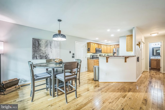 16206 Tiffany Ln, Haymarket, VA 20169 - kitchen featuring appliances with stainless steel finishes, a peninsula, light wood-style floors, recessed lighting, and a breakfast bar