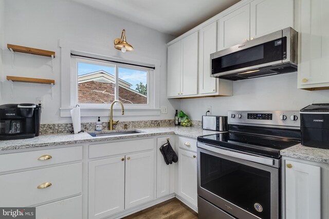 4006 6th St, North Beach, MD 20714 - kitchen featuring appliances with stainless steel finishes, white cabinetry, open shelves, wood finished floors, and light stone countertops