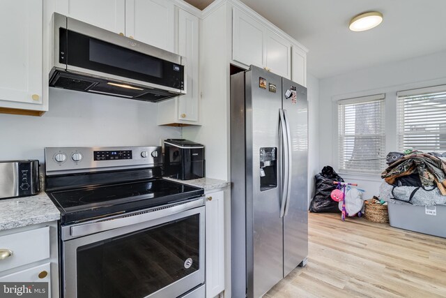 4006 6th St, North Beach, MD 20714 - kitchen featuring appliances with stainless steel finishes, white cabinetry, light wood-type flooring, and light stone counters