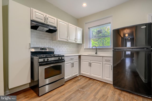 2557 W Baltimore St, Baltimore, MD 21223 - kitchen featuring freestanding refrigerator, gas stove, under cabinet range hood, light countertops, and light wood-style flooring