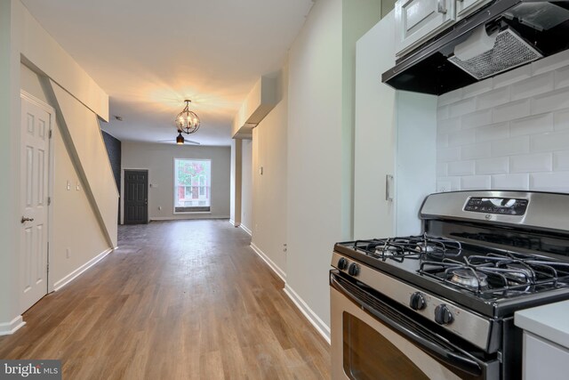 2557 W Baltimore St, Baltimore, MD 21223 - kitchen featuring gas range, exhaust hood, light wood-style floors, a chandelier, and light countertops
