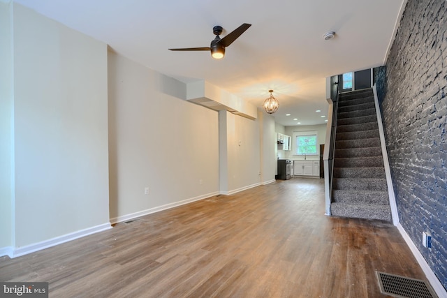 2557 W Baltimore St, Baltimore, MD 21223 - unfurnished living room featuring wood finished floors, a ceiling fan, stairway, and a chandelier