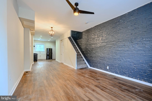 2557 W Baltimore St, Baltimore, MD 21223 - unfurnished living room featuring a chandelier, wood finished floors, ceiling fan, and stairs