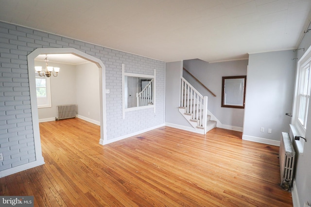 652 Windsor St, York, PA 17403 - spare room featuring radiator heating unit, wood-type flooring, stairway, brick wall, and a chandelier