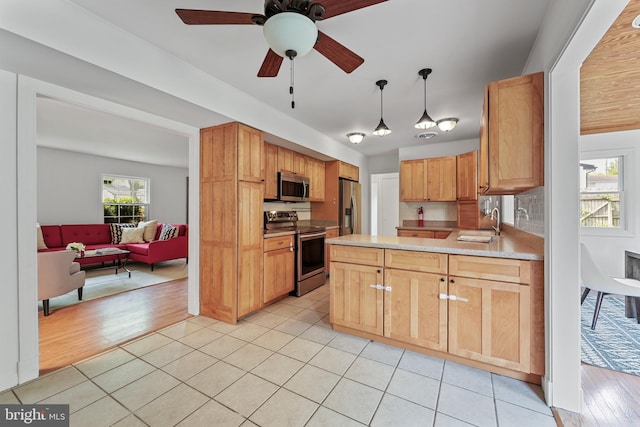 2818 Spiral Ln, Bowie, MD 20715 - kitchen featuring stainless steel appliances, a peninsula, light countertops, light tile patterned floors, and decorative light fixtures