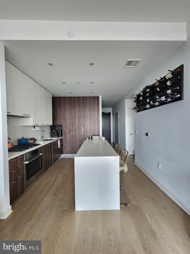 1650 Silver Hill Dr Unit 1608, Mclean, VA 22102 - kitchen with appliances with stainless steel finishes, modern cabinets, white cabinetry, light wood-style flooring, and light countertops