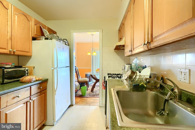 8308 Flower Ave Unit 401, Takoma Park, MD 20912 - kitchen with under cabinet range hood, decorative backsplash, light floors, hanging light fixtures, and freestanding refrigerator