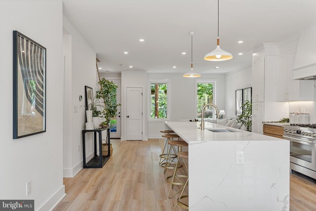 4308 4th St NW, Washington, DC 20011 - kitchen with gas range, white cabinets, light stone countertops, a kitchen bar, and light wood-style floors