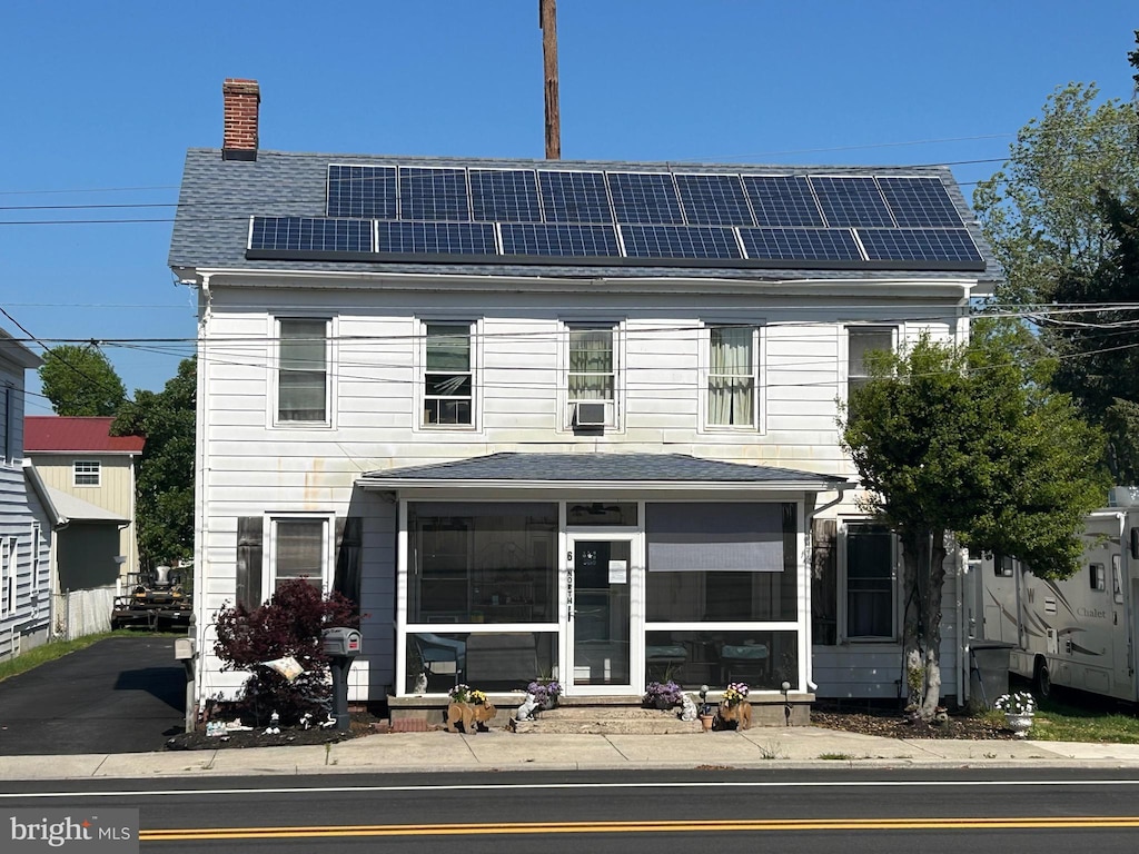 6 N Railroad Ave, Wyoming, DE 19934 - view of front of home with a sunroom, a chimney, solar panels, and roof with shingles
