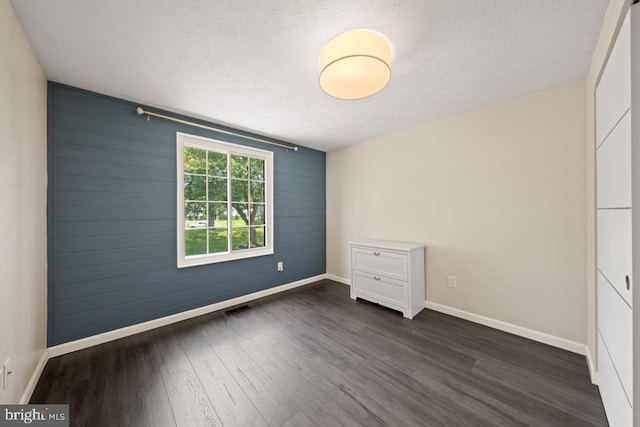 7012 Vantage Dr, Alexandria, VA 22306 - unfurnished bedroom with dark wood-type flooring, a textured ceiling, and wooden walls