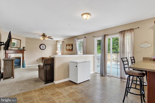 2785 Sparrow Dr, York, PA 17408 - kitchen featuring white fridge, ceiling fan, a kitchen breakfast bar, a fireplace with flush hearth, and light countertops