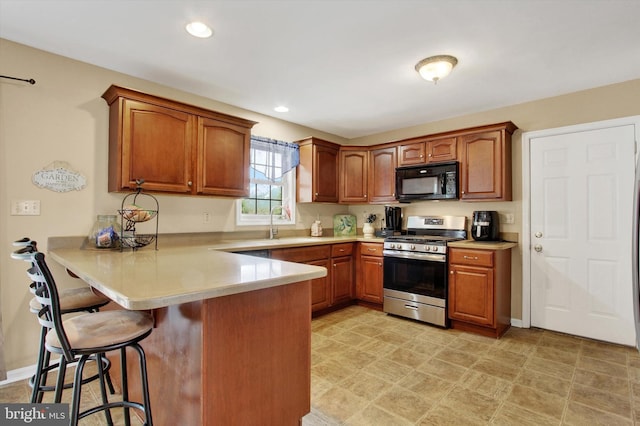 2785 Sparrow Dr, York, PA 17408 - kitchen with stainless steel range with gas cooktop, black microwave, a breakfast bar area, a peninsula, and light countertops