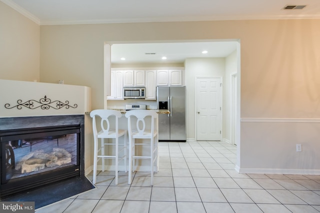 19967 Sandy Bottom Cir Unit 103, Rehoboth Beach, DE 19971 - kitchen featuring stainless steel appliances, white cabinets, a breakfast bar area, a glass covered fireplace, and light countertops