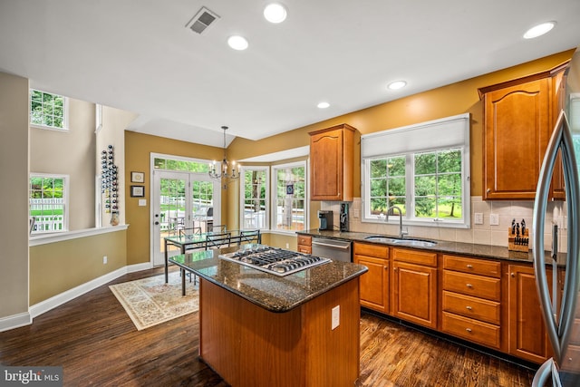 1 Ralph Marsh Dr, Glen Mills, PA 19342 - kitchen featuring stainless steel appliances, a center island, brown cabinetry, dark stone counters, and plenty of natural light