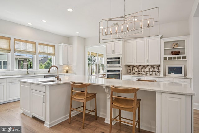 41550 Hepatica Ct, Ashburn, VA 20148 - kitchen featuring tasteful backsplash, recessed lighting, a kitchen island with sink, light wood-style floors, and white cabinets