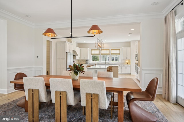 41550 Hepatica Ct, Ashburn, VA 20148 - dining room with light wood-style floors, a decorative wall, wainscoting, and ornamental molding