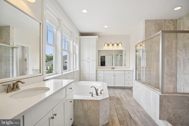 41550 Hepatica Ct, Ashburn, VA 20148 - full bath featuring a stall shower, two vanities, a bath, recessed lighting, and wood finished floors