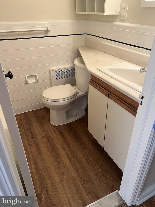 846 Windermere Ave, Drexel Hill, PA 19026 - bathroom featuring tile walls, vanity, radiator heating unit, wood finished floors, and a wainscoted wall
