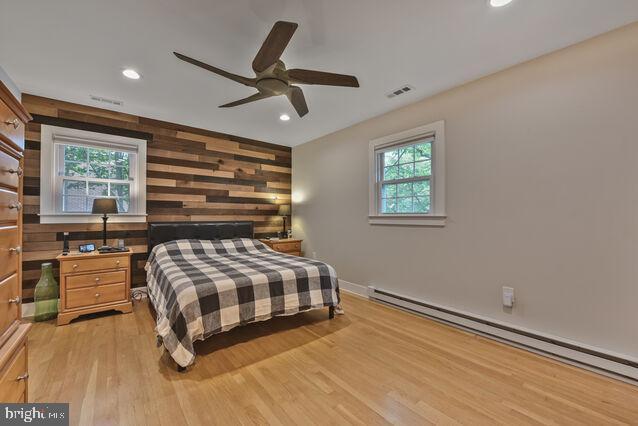32 Hamilton Terrace Dr, Hamilton, VA 20158 - bedroom with a baseboard heating unit, light wood finished floors, wooden walls, recessed lighting, and an accent wall