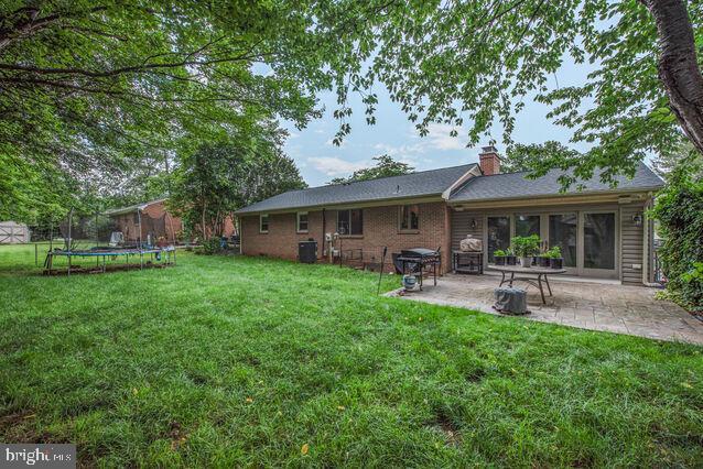 32 Hamilton Terrace Dr, Hamilton, VA 20158 - back of house with a trampoline, a patio, a lawn, and a chimney