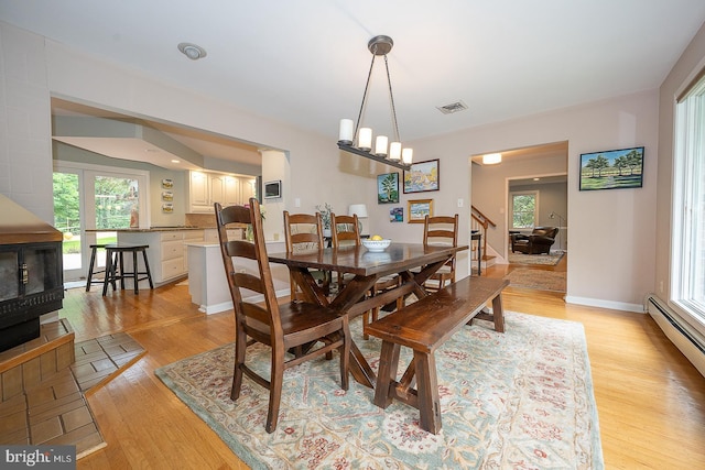 840 Old State Rd, Berwyn, PA 19312 - dining area featuring light wood-type flooring, stairway, a baseboard heating unit, a wood stove, and a chandelier