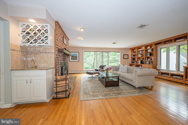 840 Old State Rd, Berwyn, PA 19312 - living area with light wood-style flooring, a bar, and a brick fireplace