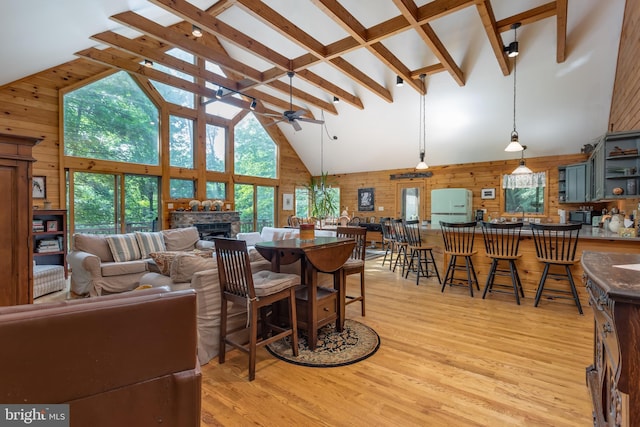 379 Wintergreen Way, Berkeley Springs, WV 25411 - living room featuring high vaulted ceiling, a ceiling fan, a stone fireplace, wooden walls, and light wood-style floors