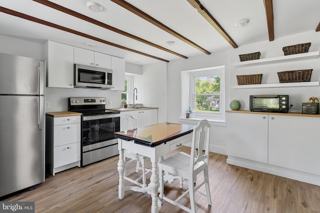 2397 Hill Rd, Perkiomenville, PA 18074 - kitchen featuring appliances with stainless steel finishes, plenty of natural light, white cabinetry, light wood-style flooring, and beam ceiling