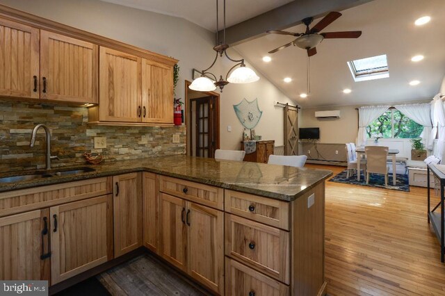 99 Old Main Shore Rd, Barnegat, NJ 08005 - kitchen featuring a ceiling fan, a peninsula, a barn door, decorative backsplash, and dark wood-style flooring